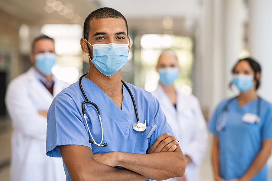 hospital employees stand in a group smiling at the camera inside a hospital.